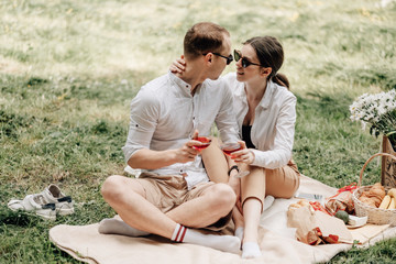 Young Happy Couple Dressed Alike in White T-shirt Having Fun on Picnic, Weekend Outside the City, Holidays Concept