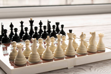 Chessboard with figures on a wooden table. Selective focus.