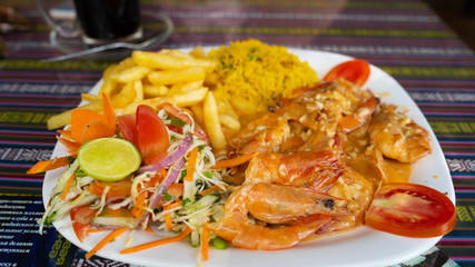 Delicious dish on restaurant table. Closeup plate of yummy dish with shrimps and french fries placed on ornamental table in cafe