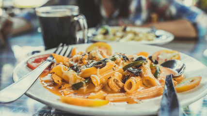 Delicious pasta with tomato sauce. Silverware placed on plate of palatable pasta with tomato sauce and olives on ornamental table in cafeteria