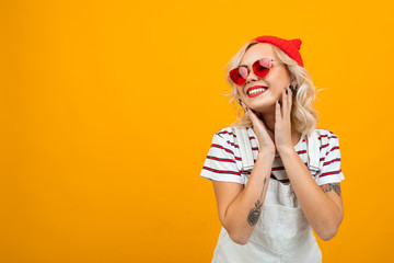 Beautiful young woman with short blonde curly hair and bright makeup in white overalls. red...