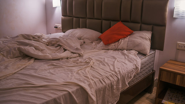 Unmade bed in modern bedroom. From above warm blanket and soft pillows placed on comfortable unmade bed in stylish contemporary bedroom