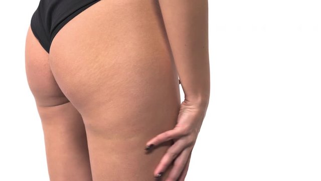 Woman checking cellulite on her butt. Female hand testing the skin for stretch marks and fat. Body care, self-confidence and weight loss