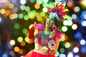 Beautiful young woman in carnival mask and stylish masquerade costume with feathers and sparklers...
