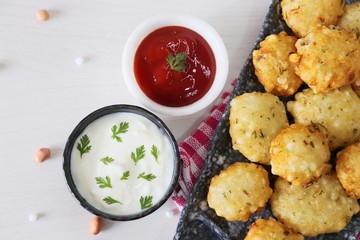 Sabudana vada or Sago fried fitters served with Curd or yogurt and ketchup over white wooden background, popular fasting recipe from India or mostly eaten during Fasting