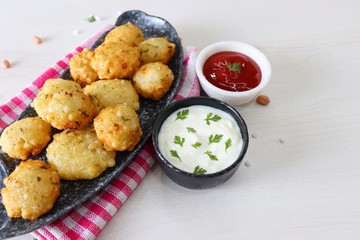 Sabudana vada or Sago fried fitters served with Curd or yogurt and ketchup over white wooden background, popular fasting recipe from India or mostly eaten during Fasting