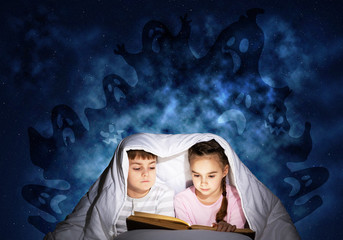 Engrossed little kids reading book in bed