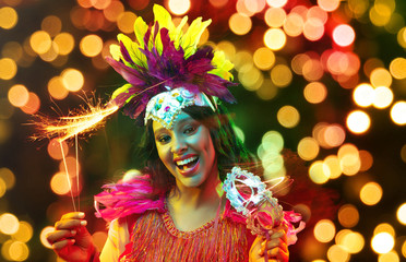 Beautiful young woman in carnival mask and stylish masquerade costume with feathers and sparklers...
