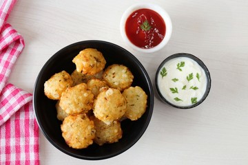 Sabudana vada or Sago fried fitters served with Curd or yogurt and ketchup over white wooden background, popular fasting recipe from India or mostly eaten during Fasting