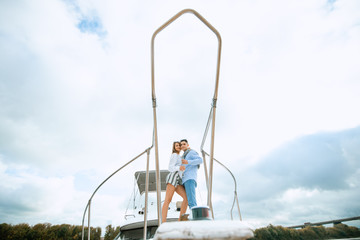 Naklejka premium Romantic couple in love on sail boat at under sunlight on yacht. Happy exclusive alternative lifestyle concept. Love story of two lovers. Two young tourists having fun on boat tour in the summertime