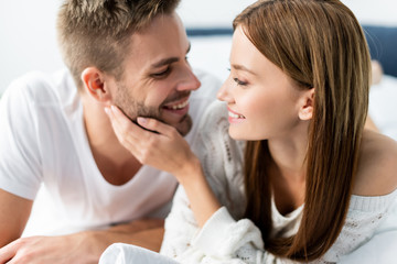 attractive and smiling woman looking at handsome man in apartment