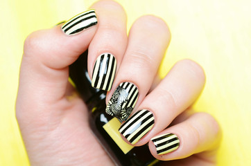 Bright yellow manicure with black stripes and sunflowers pattern on yellow background
