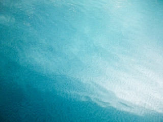 The texture of the blue surface of the water in the pool. Blue​ water​ background.