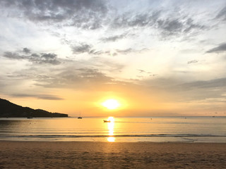 fishing boat is sailing into the middle of golden sunset light with amazing twilight sky and yachts in clear sea