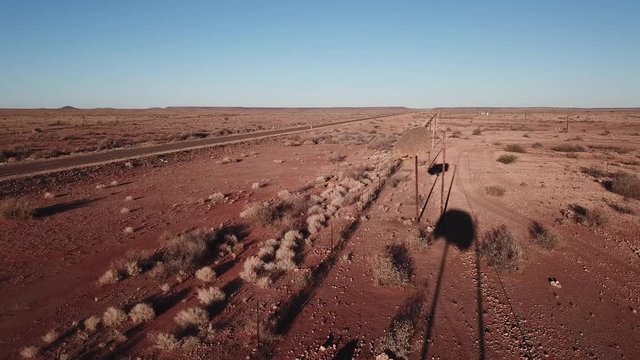 4K aerial drone video of sociable weavers nests on power pillars, gravel plains, wide dry bush savanna panorama near Upington, South Africa, N10 desert highway near Namibian border, southern Africa