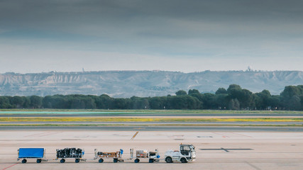Fototapeta premium Freight trolleys with loaded baggage on the runway tarmac