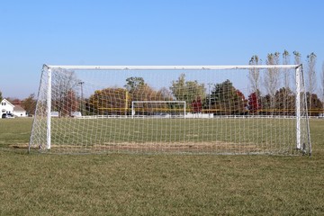 Fototapeta premium A view behind the white soccer goal net in the field.