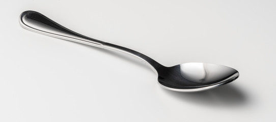 Silver dessert spoon cutlery on grey background