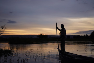 Malian Fisherman Manouevring His Boat Along The Niger Riverside AT Sunset