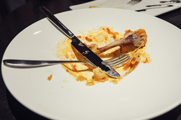 Dirty plate with appliances and bone on the table.
