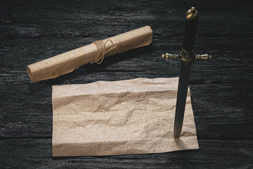 Pirate treasure map template and dagger in wooden table.
