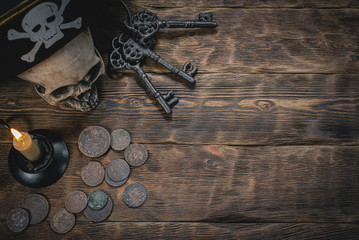 Pirate hat, treasure coins and keys from old chest on the wooden desk background with copy space.