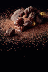 Various chocolate candies with chocolate chips on a black reflective background.