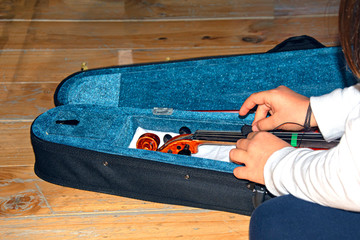Manos de niña guardando el violín en su funda / Girl's hands keeping the violin in its case