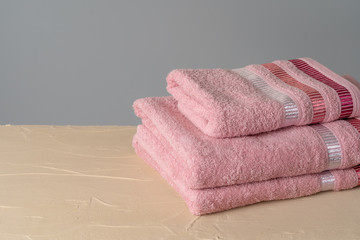 Fototapeta na wymiar Pile of clean new towels against grey wall
