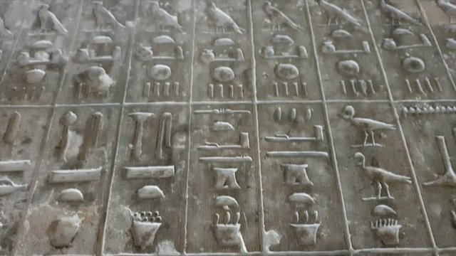 Close up of Egyptian hieroglyphics letters on wall at ancient architecture