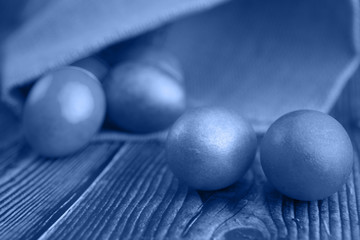 Colored Easter eggs on a wooden background in burlap with blurred background, toned trendy classic blue color of year 2020