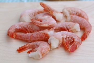 Several pieces of shrimp frozen before cooking thaw on a round board