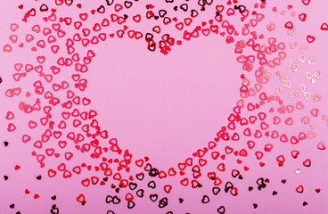 Valentine's day red hearts glitter in heart shape frame on pink background, holyday background