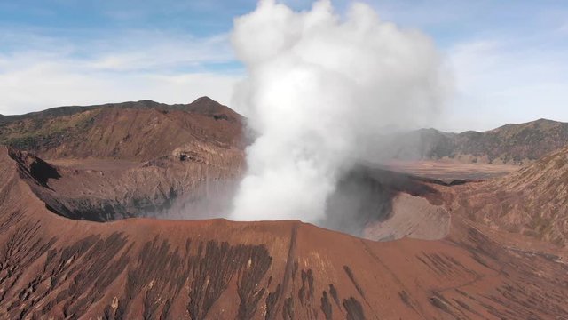 Aerial shot of smoking Mount Bromo, full crater shot, horizon view, slightly rotating. Java, Indonesia