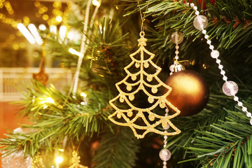 Golden ball and Golden christmas tree model hanging on the branches of the Christmas tree, Christmas background with festive decorations, solf fous.