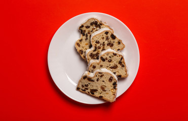slices of christmas cake with raisins on a white plate, on a red background