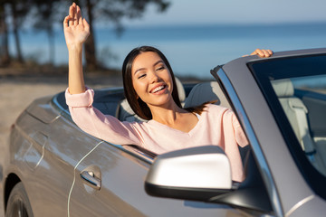 asian girl waving hand from cabriolet