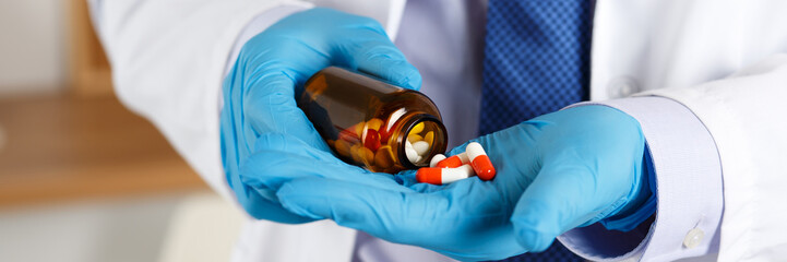 Male medicine doctor hands in blue gloves holding and offering pile of pills - Powered by Adobe