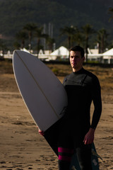 Caucasian boy with a black neoprene prepared to surf .