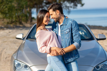 side view of man and woman hugging together at the car outdoors