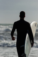 Caucasian boy with a black neoprene prepared to surf .