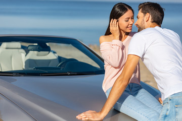 asian woman sitting on the car and man trying to kiss her