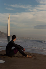 Caucasian boy with a black neoprene prepared to surf .
