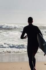 Caucasian boy with a black neoprene prepared to surf .