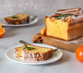Fresh orange or tangerine yogurt loaf cake with spices (cinnamon and anise) and sugar powder. Homemade cake on a light grey background.
