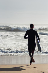 Caucasian boy with a black neoprene prepared to surf .