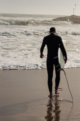 Caucasian boy with a black neoprene prepared to surf .