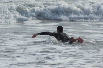 Caucasian boy with a black neoprene prepared to surf .