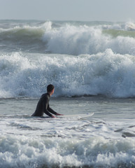 Caucasian boy with a black neoprene prepared to surf .