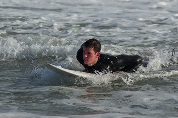 Caucasian boy with a black neoprene prepared to surf .